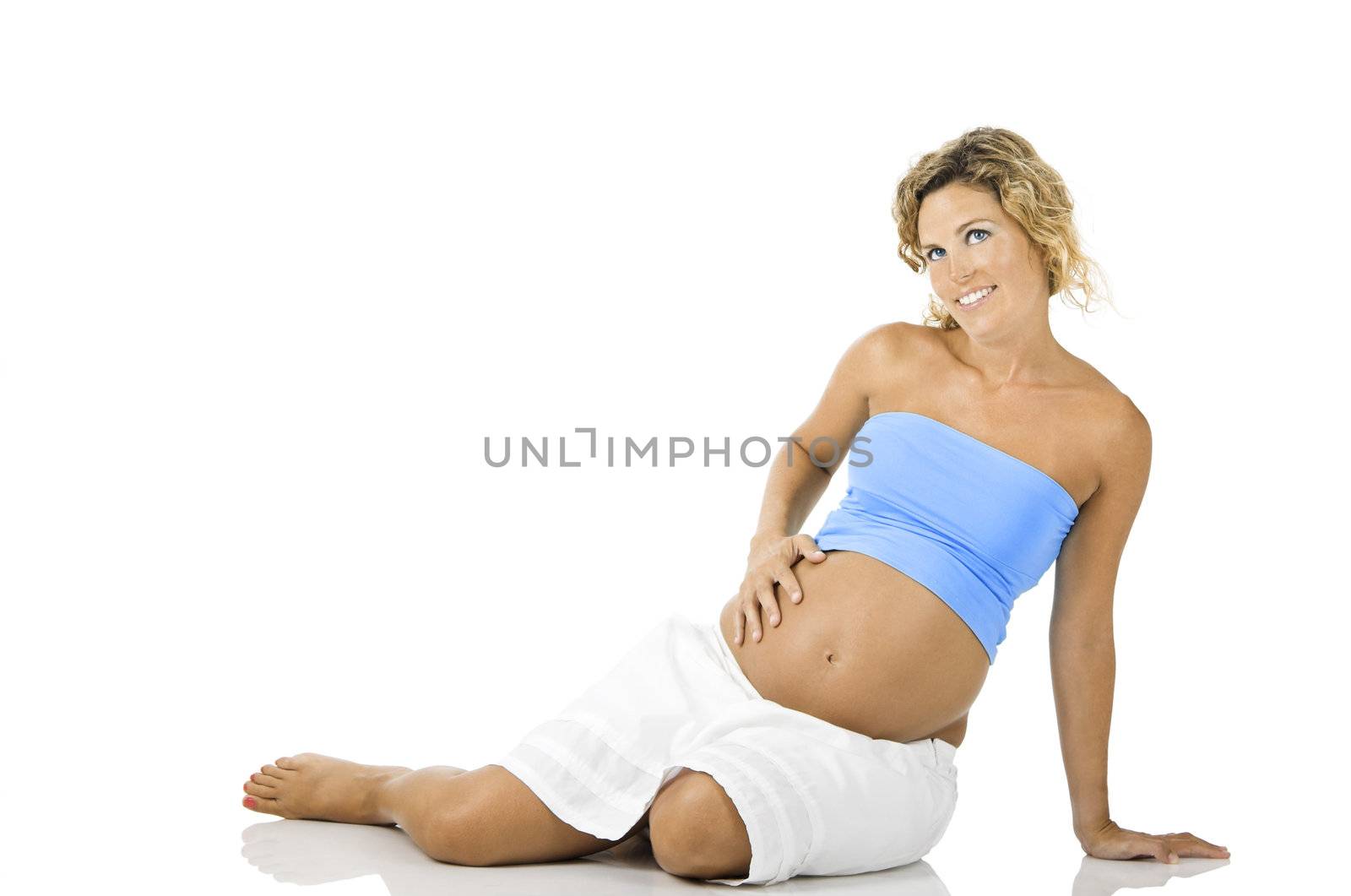 Beautiful pregnant woman seated on the floor and isolated on white background 
