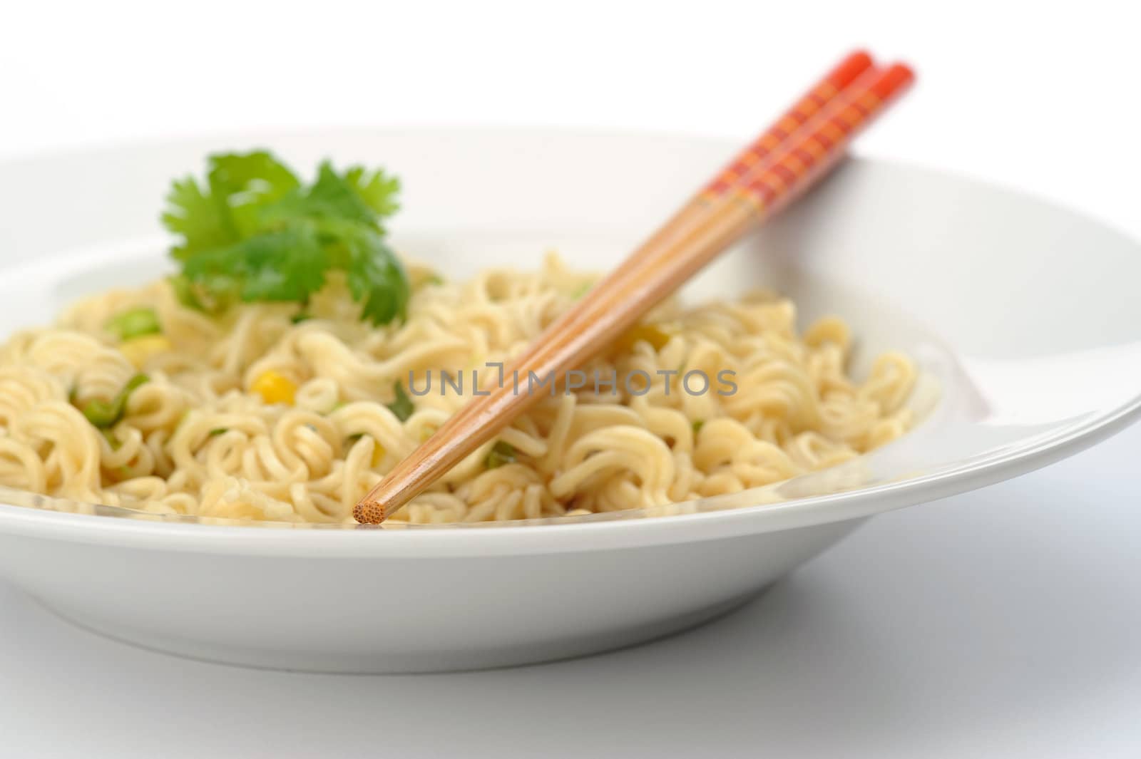 Closeup of chopsticks over a bowl of oriental style noodles.