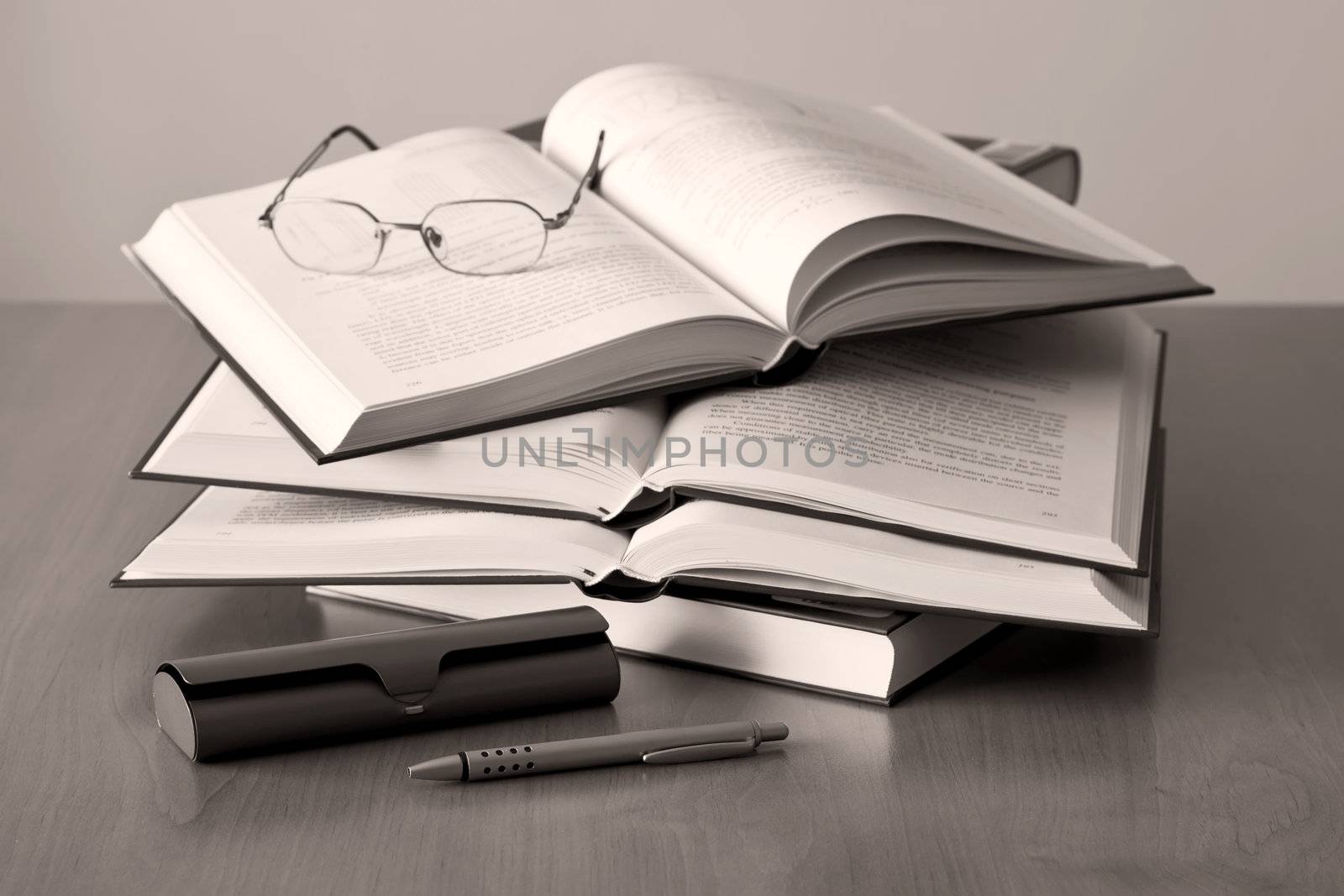 opened books pen and glasses on sepia background by artush