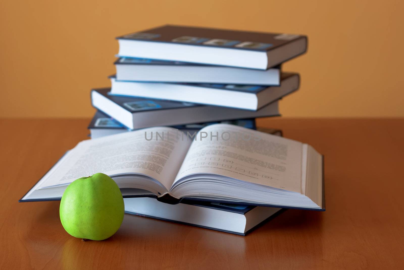 green apple and opened books on the desk by artush