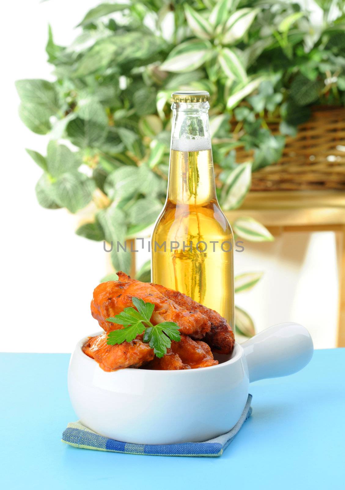 Bowl of baked spicy chicken wings and a cold beer.