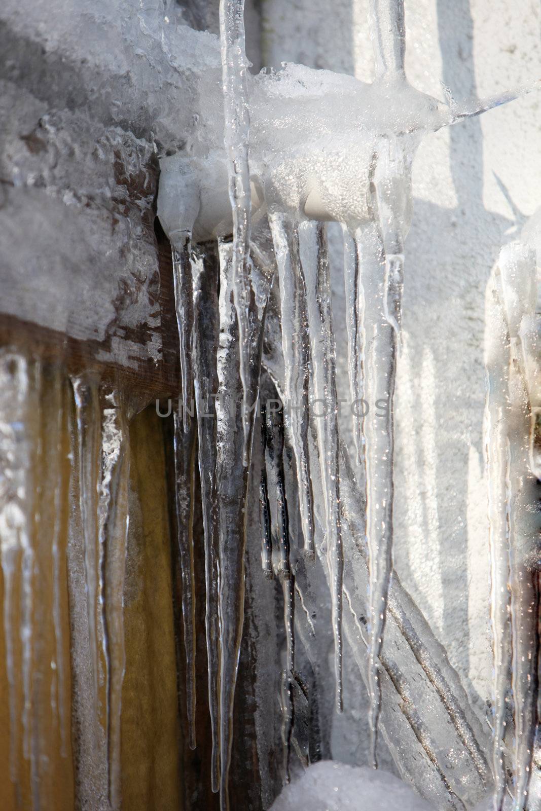 large icicles on the house wall, roof gutter and down pipe-close-up
