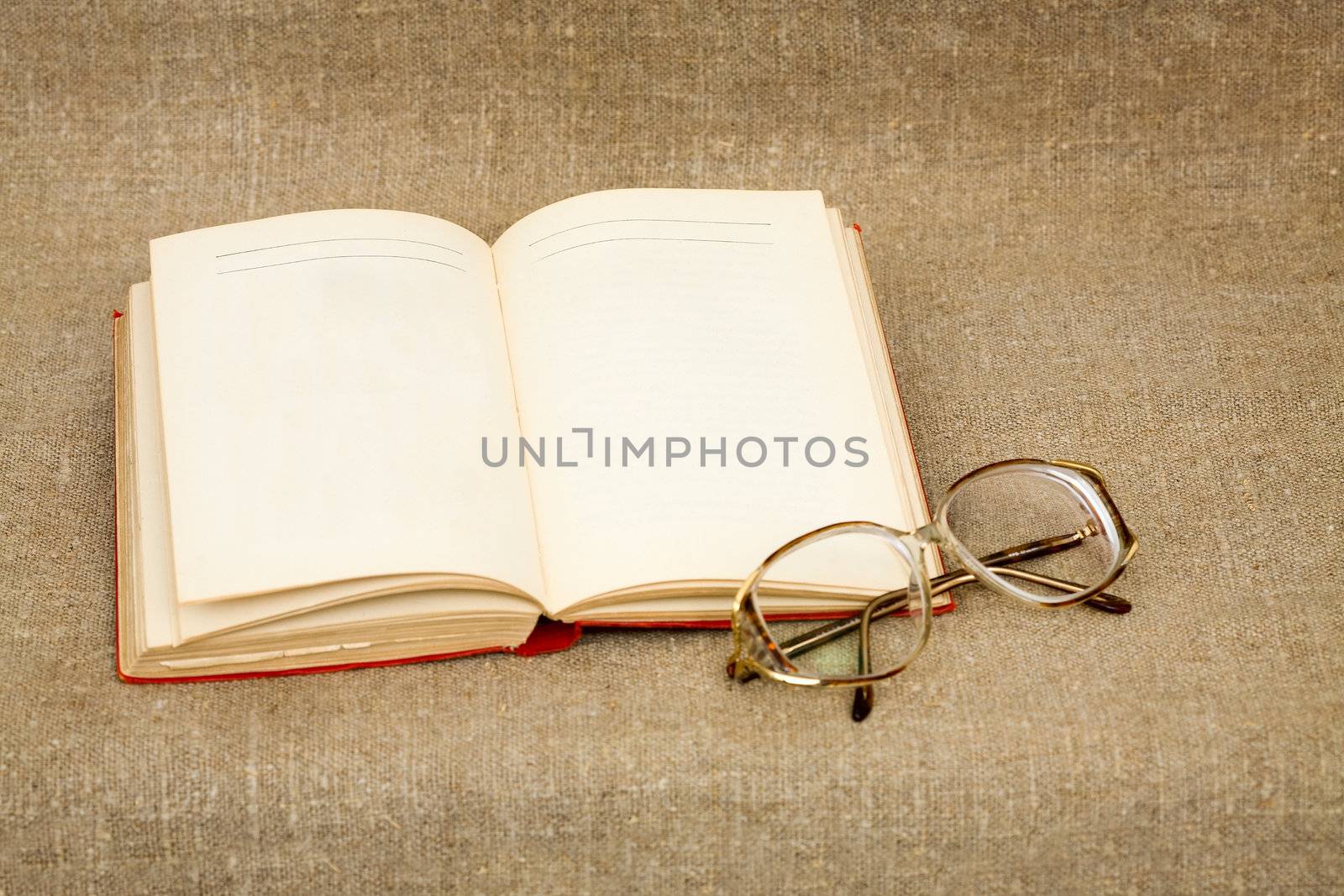 Ancient book and spectacles on the fabric background