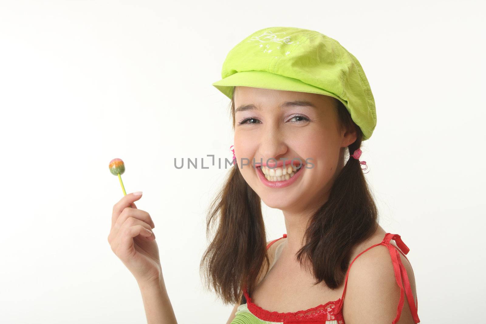 The girl in a green cap eats a sugar candy