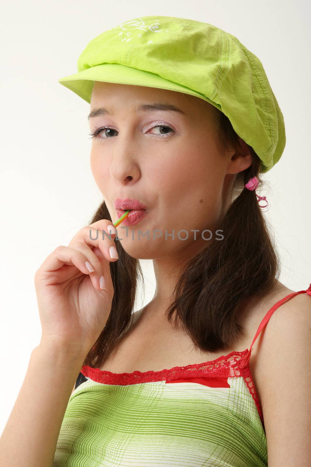 The girl in a green cap eats a sugar candy