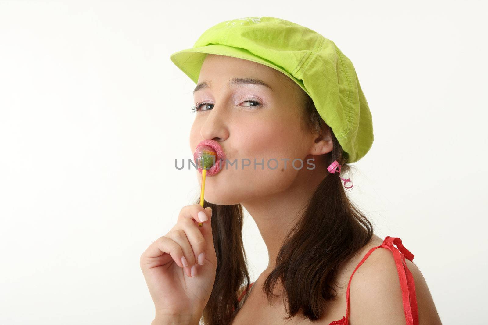 The girl in a green cap eats a sugar candy