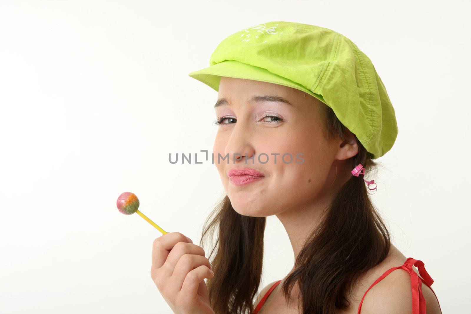 The girl in a green cap eats a sugar candy