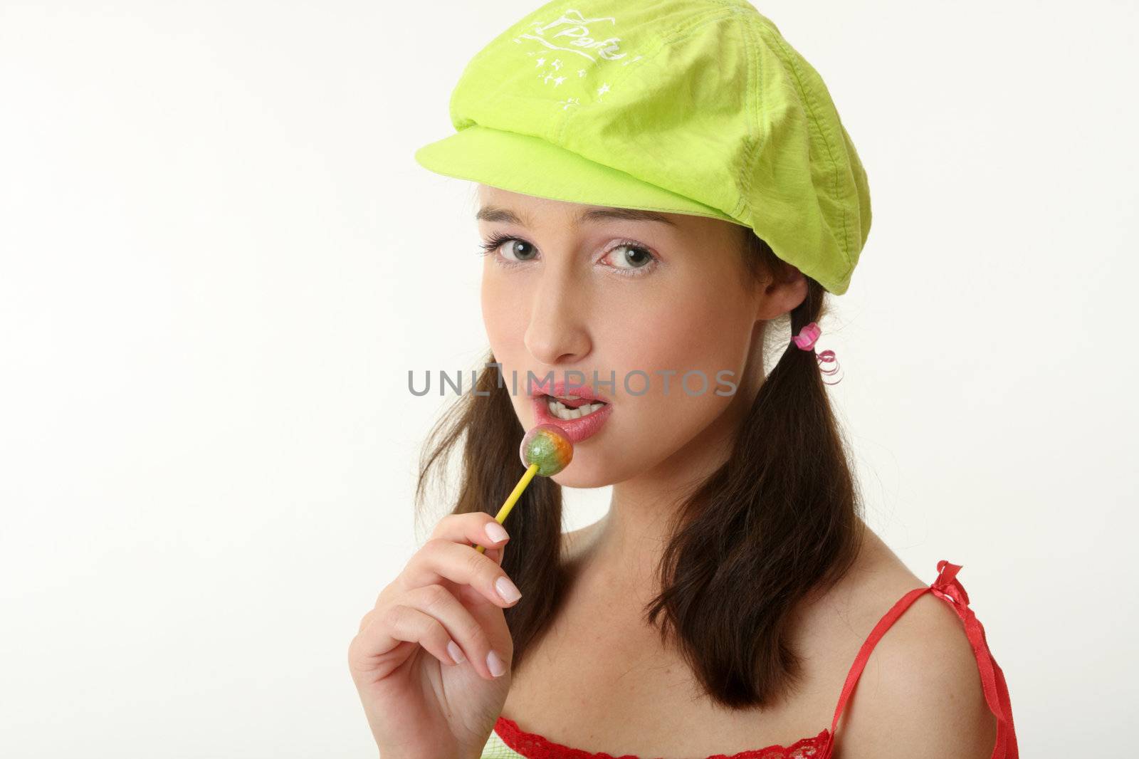 The girl in a green cap eats a sugar candy