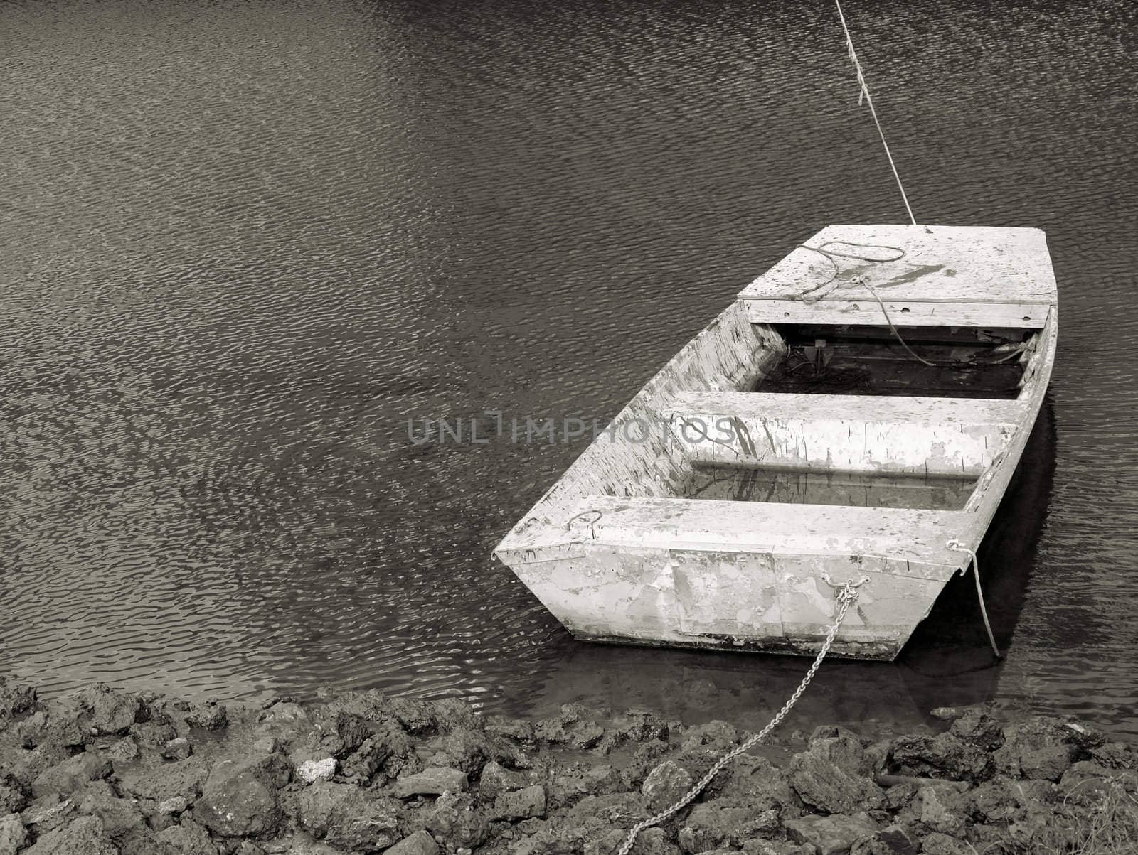 Old boat along the shore in very poor condition shown in black and white