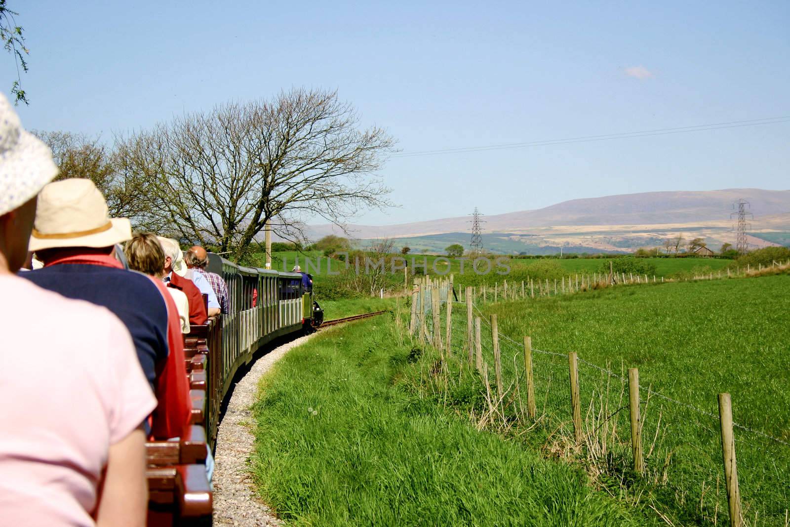 narrow gauge passenger train filled with tourists travelling through the countryside