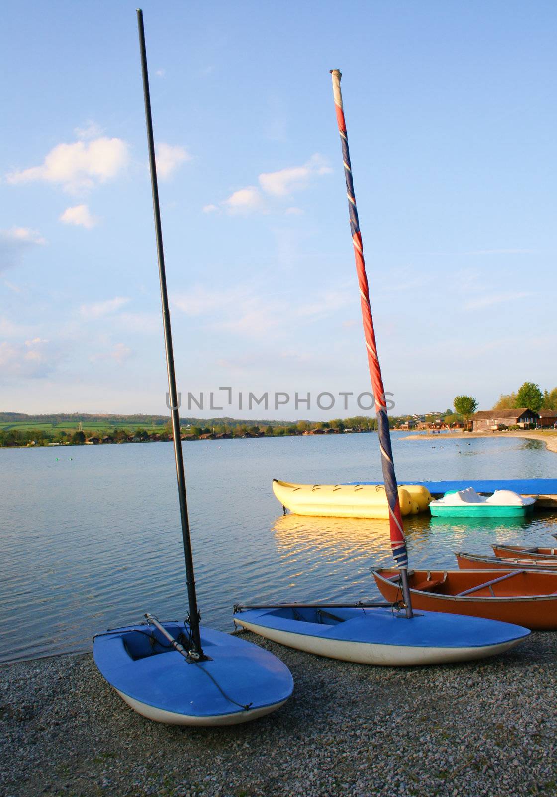 one man sailing boats on the side of a lake 