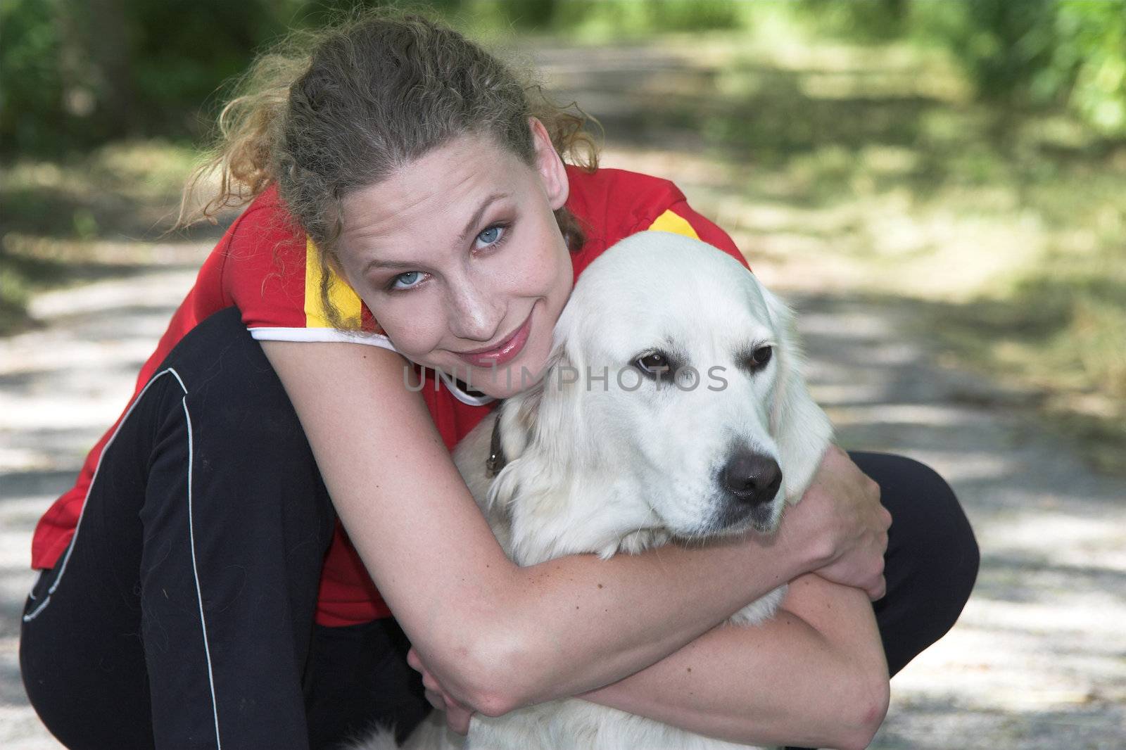 Pretty blond woman hugging her dog outdoors after having gone for a run