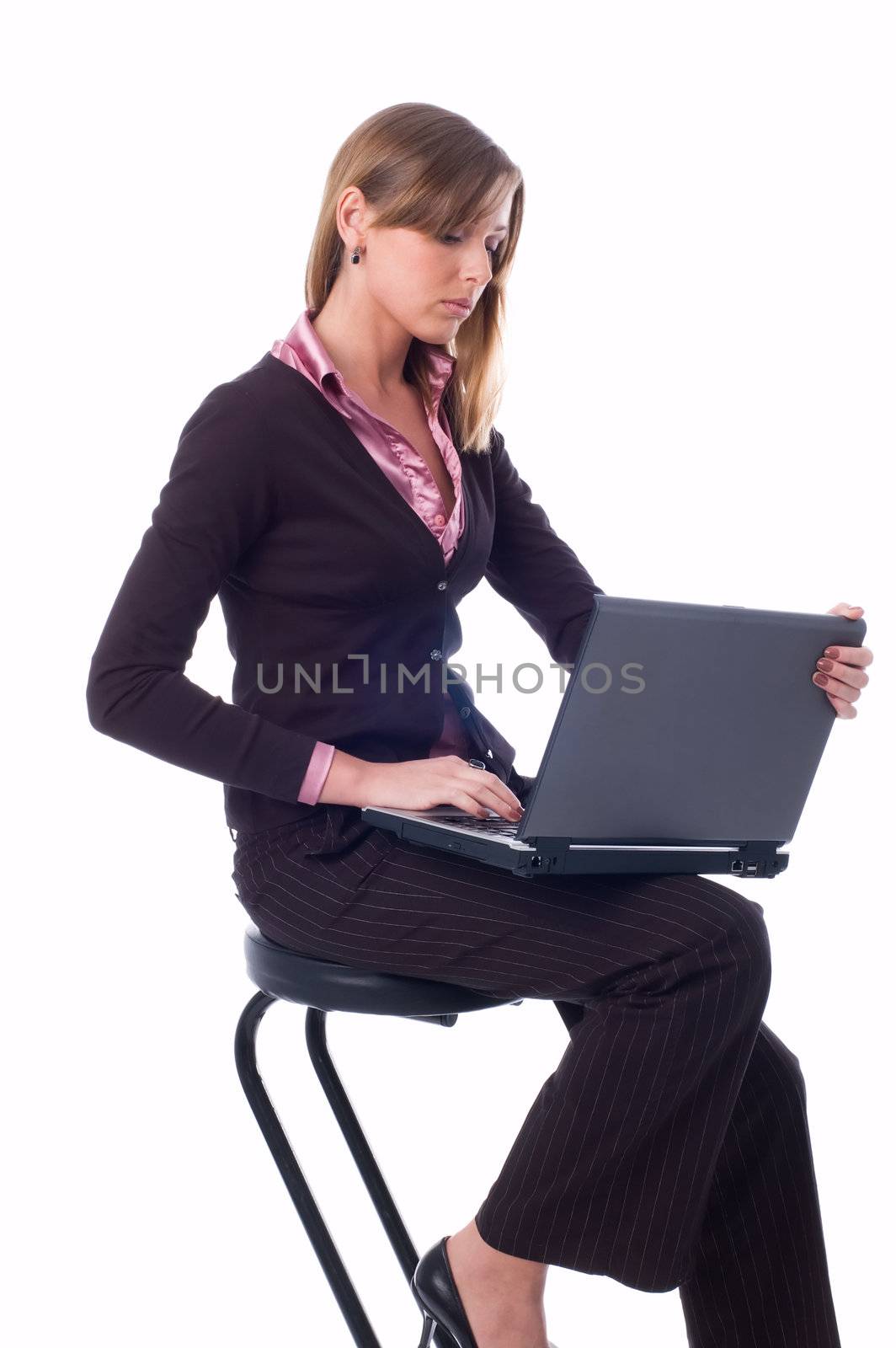 The girl sits on a high chair and works on a laptop