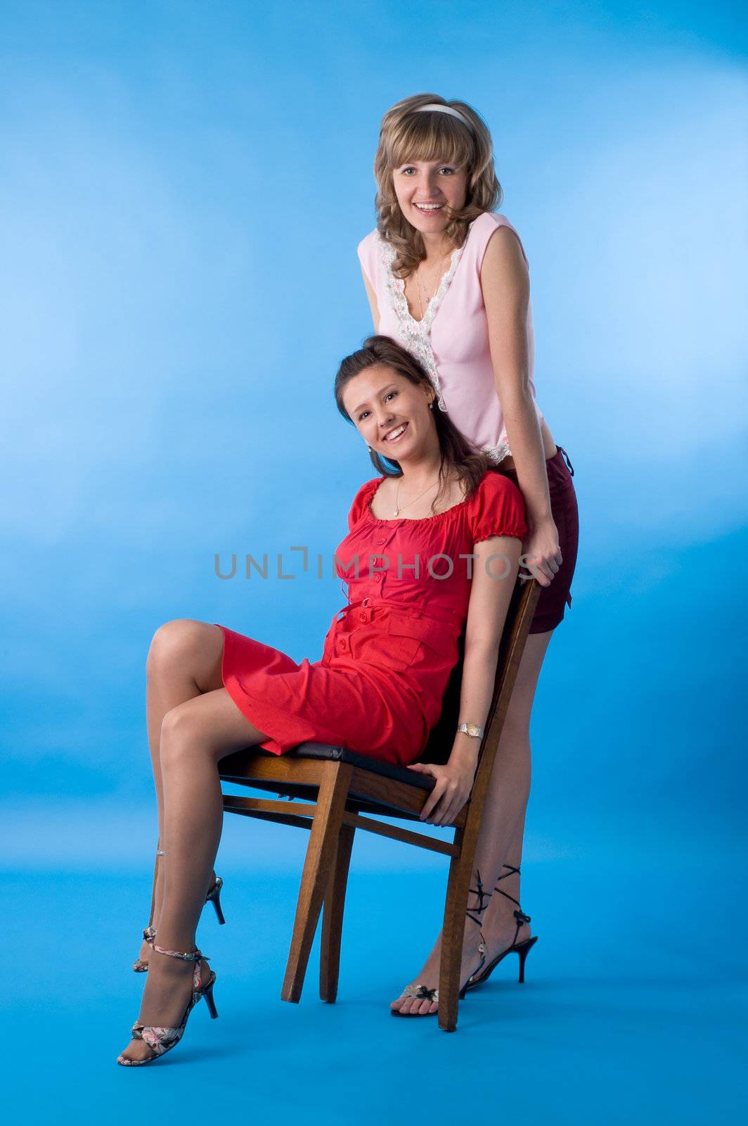 Two girls talk and pose on a blue background