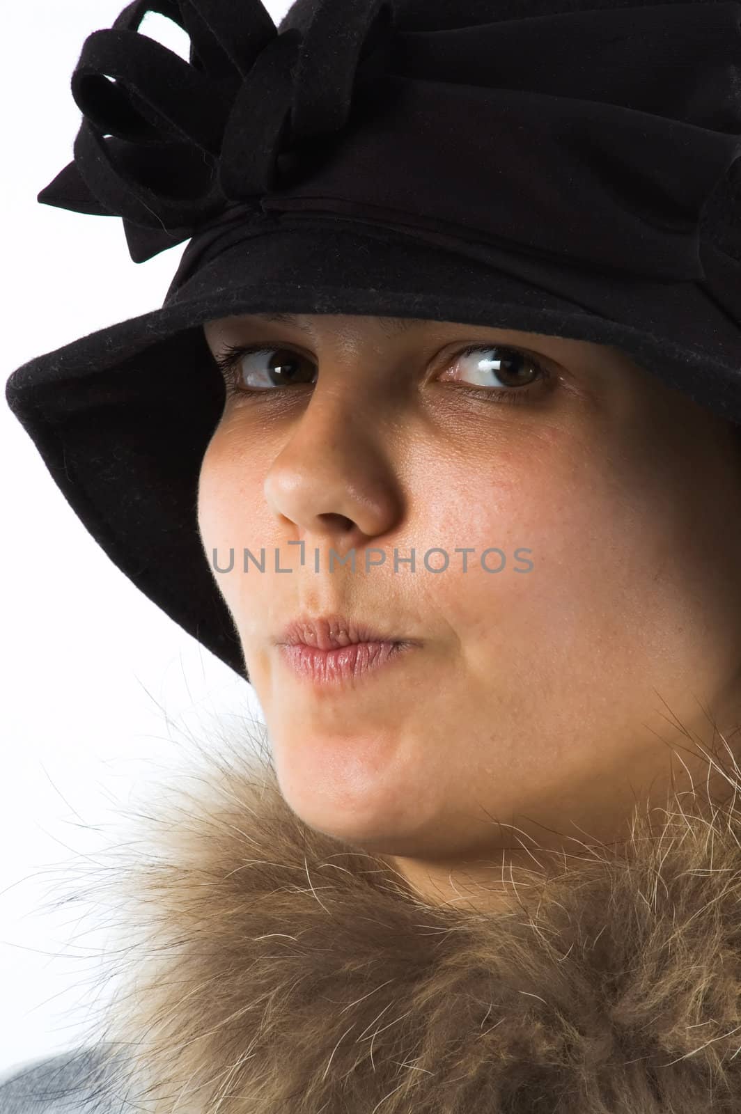 The girl in a hat has drawn in lips and looks at the photographer