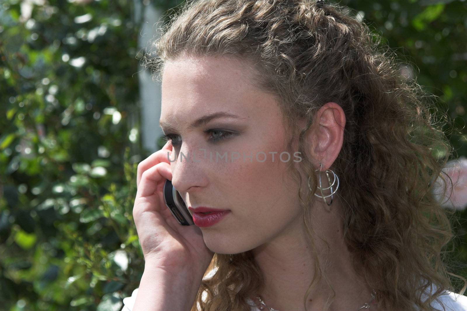 Beautiful businesswoman talking on the phone outdoors during her lunchbreak in the park