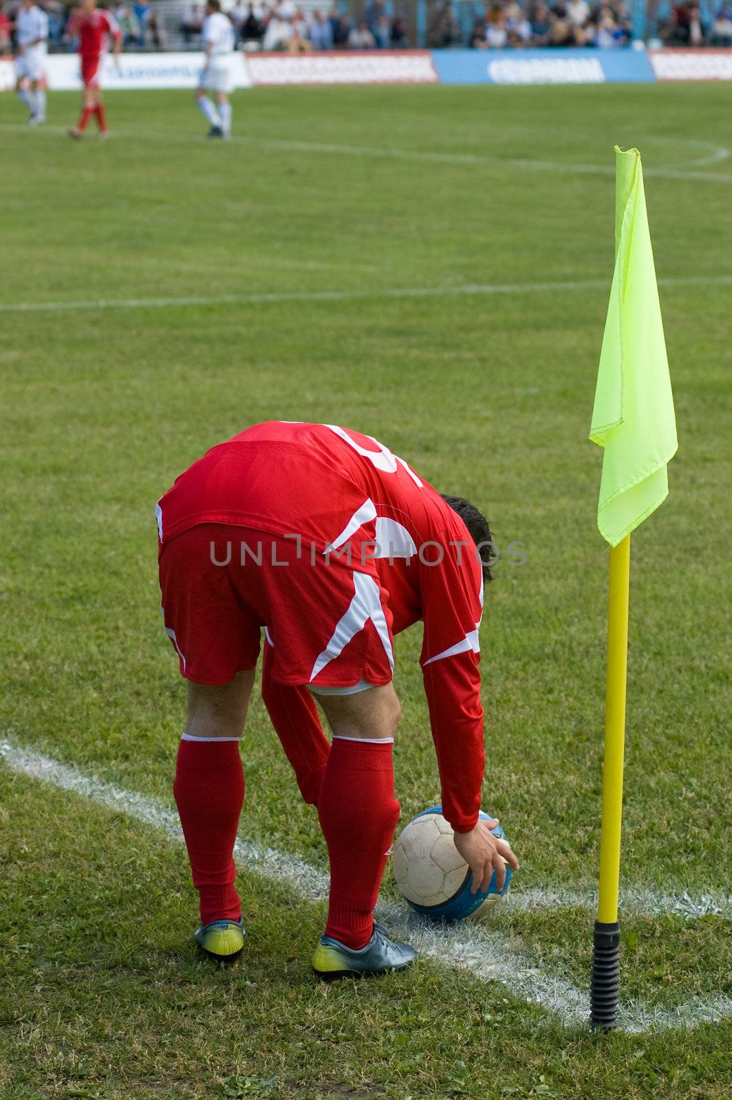 The football player in the red form carries out corner kick