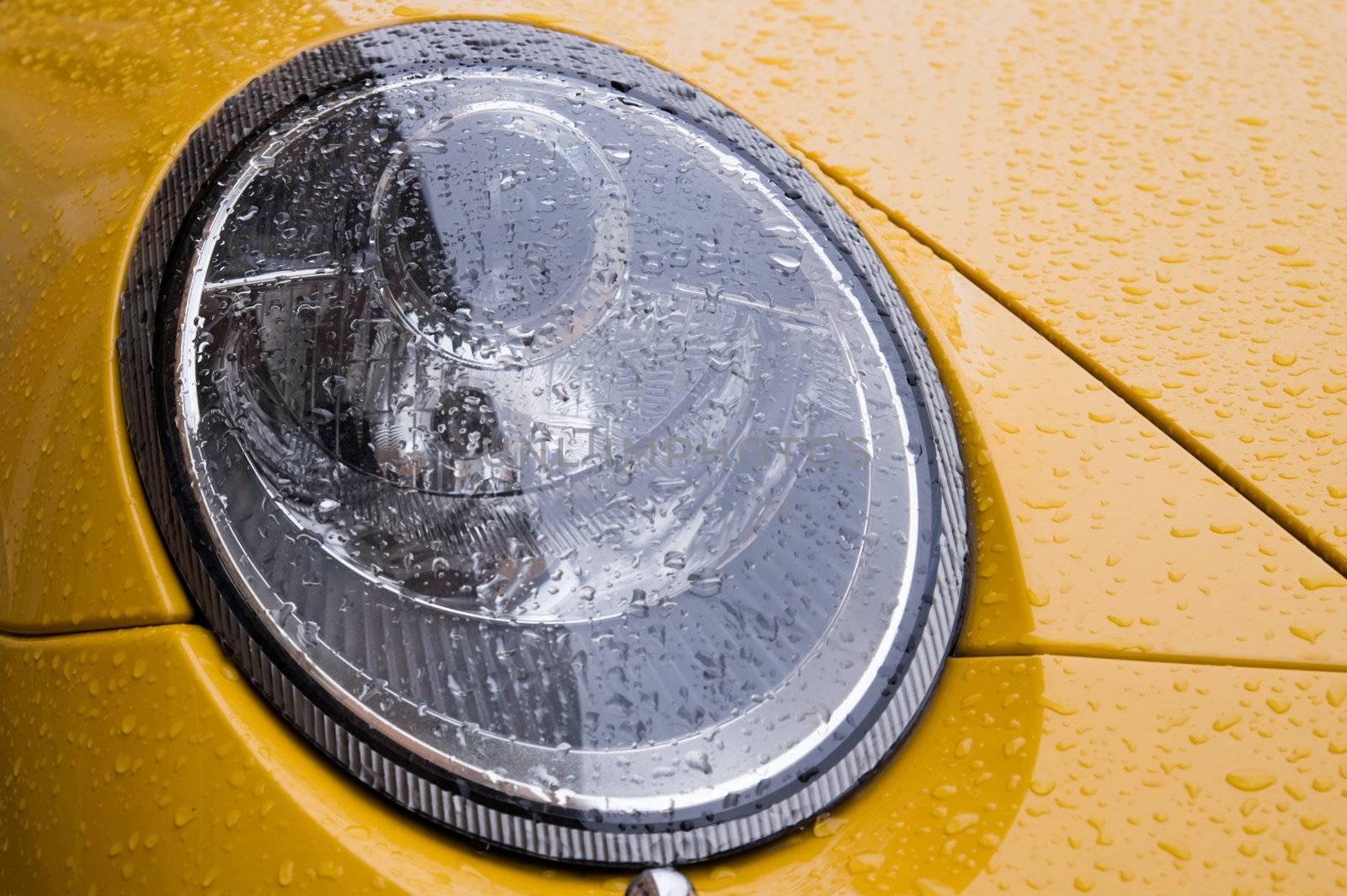 Detail of the wet yellow car in city street