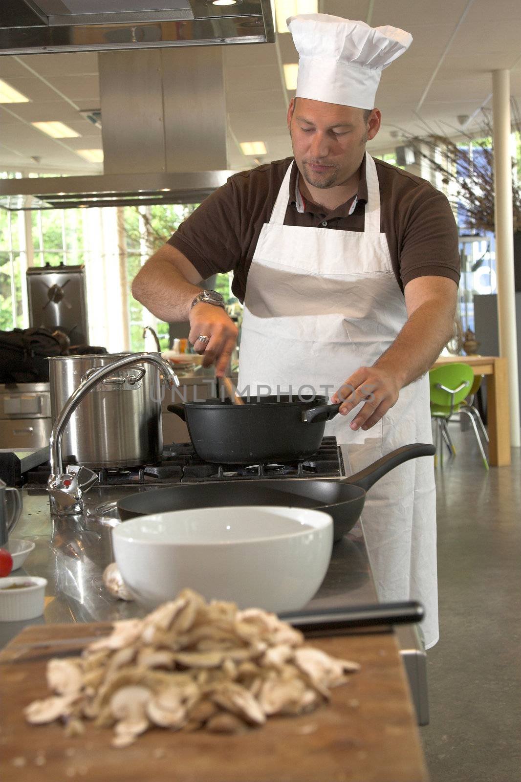 Italian chef stirring the food (shallow DOF, focus on chef)