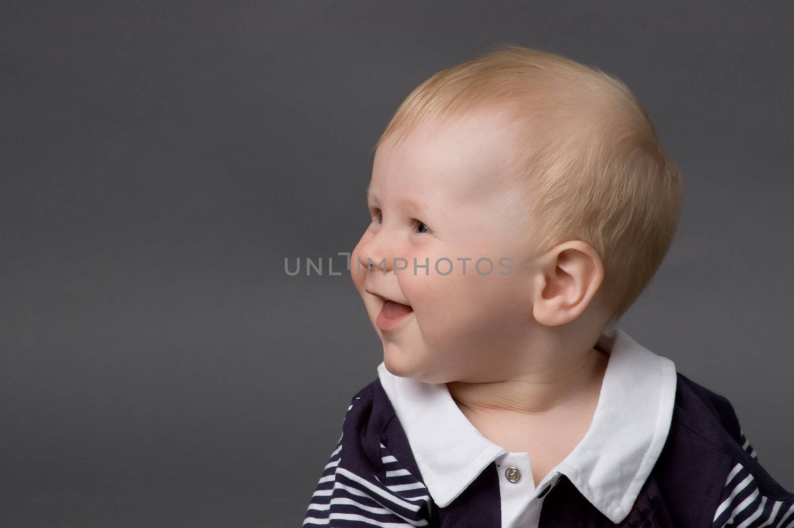 The small smiling child in studio, on a grey background