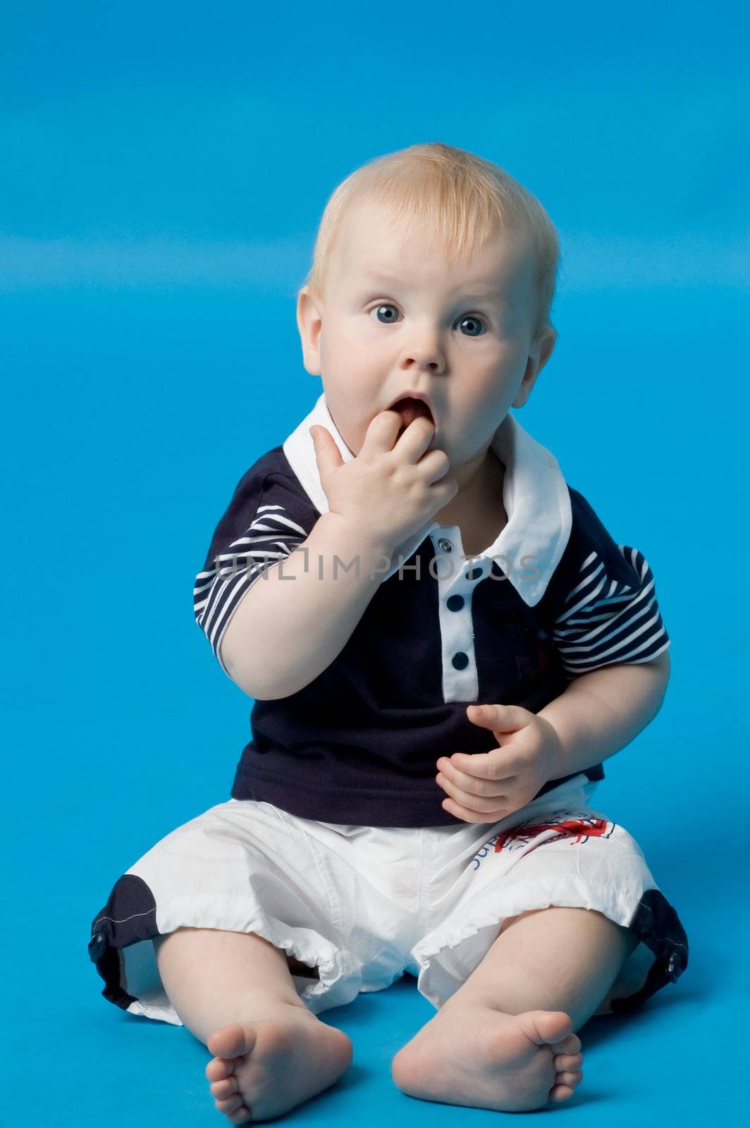 The small smiling child in studio, on a blue background