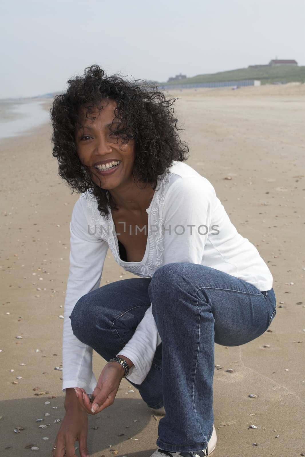 Beautiful black woman seeking shells on the beach