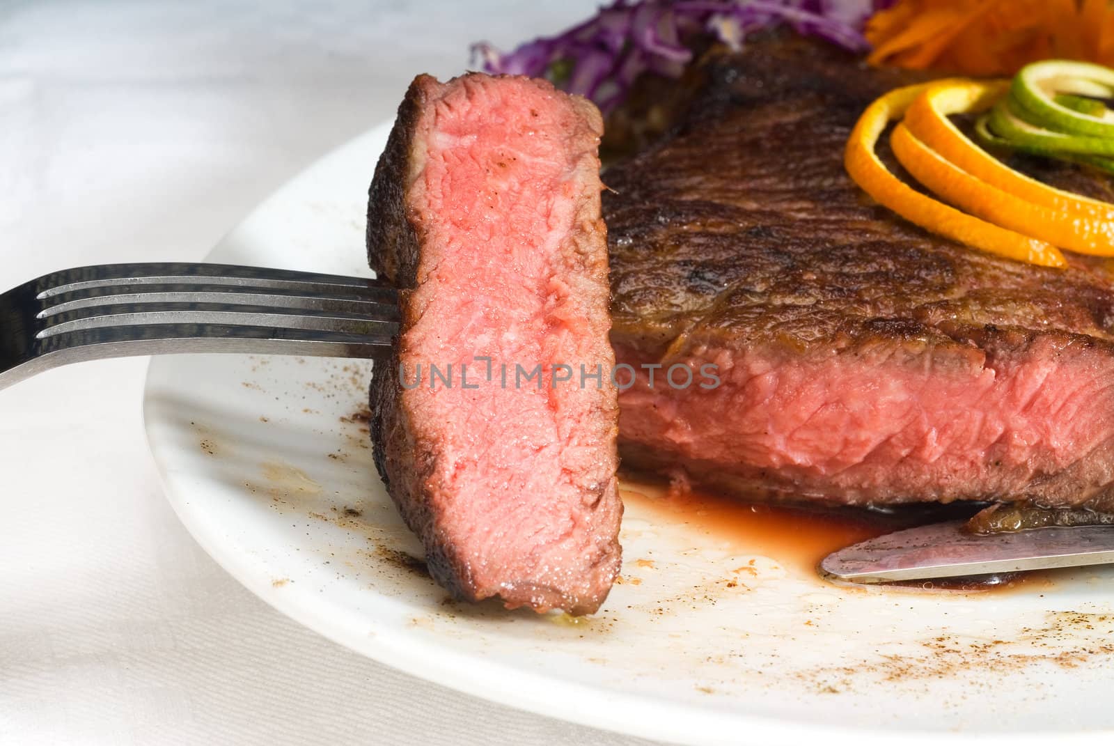 fresh juicy beef ribeye steak sliced ,with lemon and orange peel on top  and vegetable beside