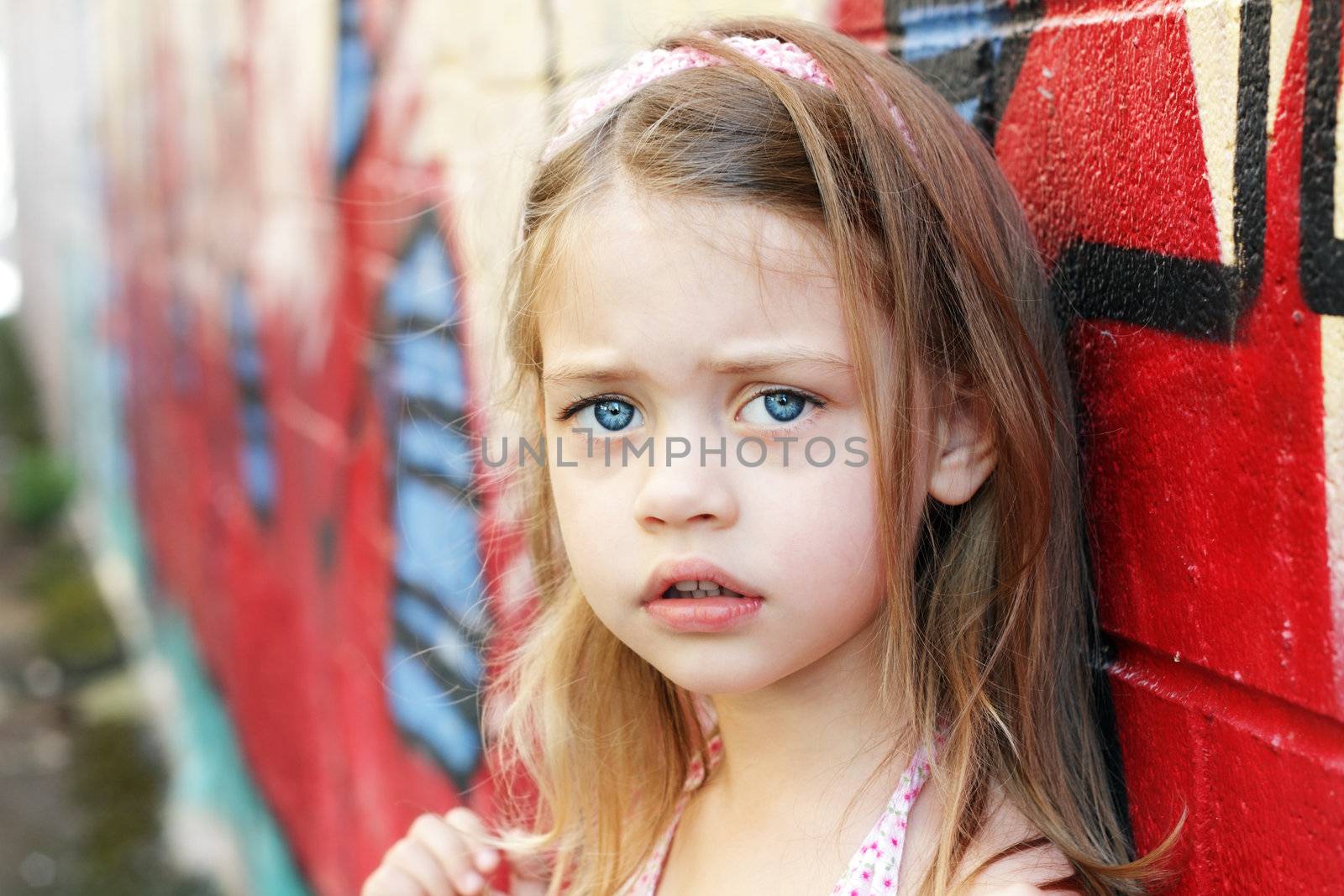 Worried little girl in an urban setting looking into the camera.