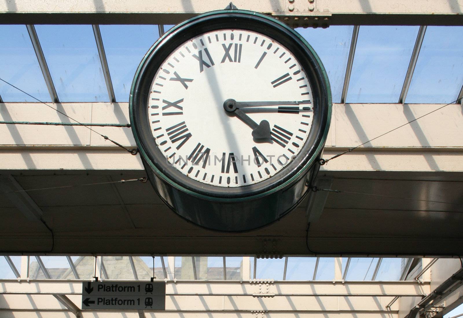 large station clock suspended above the platform of a railway station