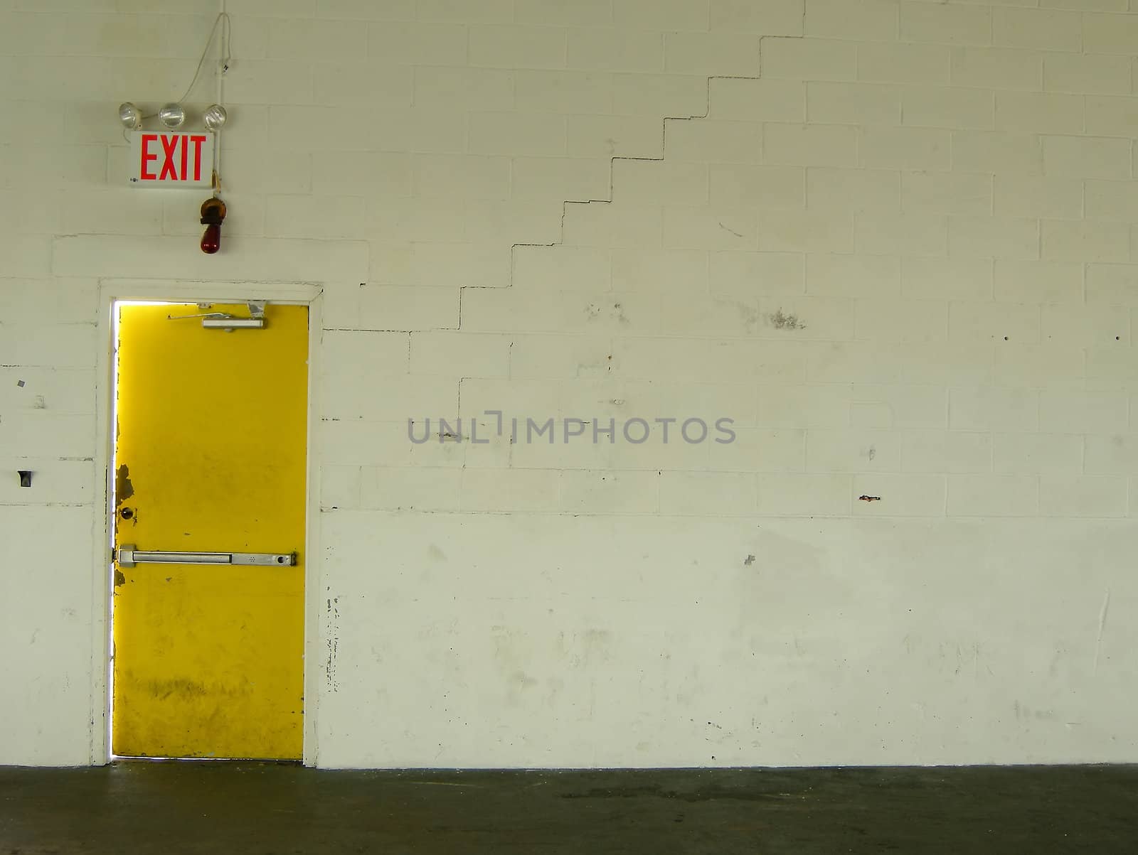 conceptual photo of a yellow exit door and old white wall