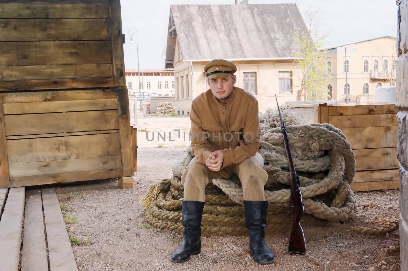 Soldier with a gun in uniform of World War I, sit down on the rope. Costume accord the times of World War I. Photo made at cinema city Cinevilla in Latvia.
