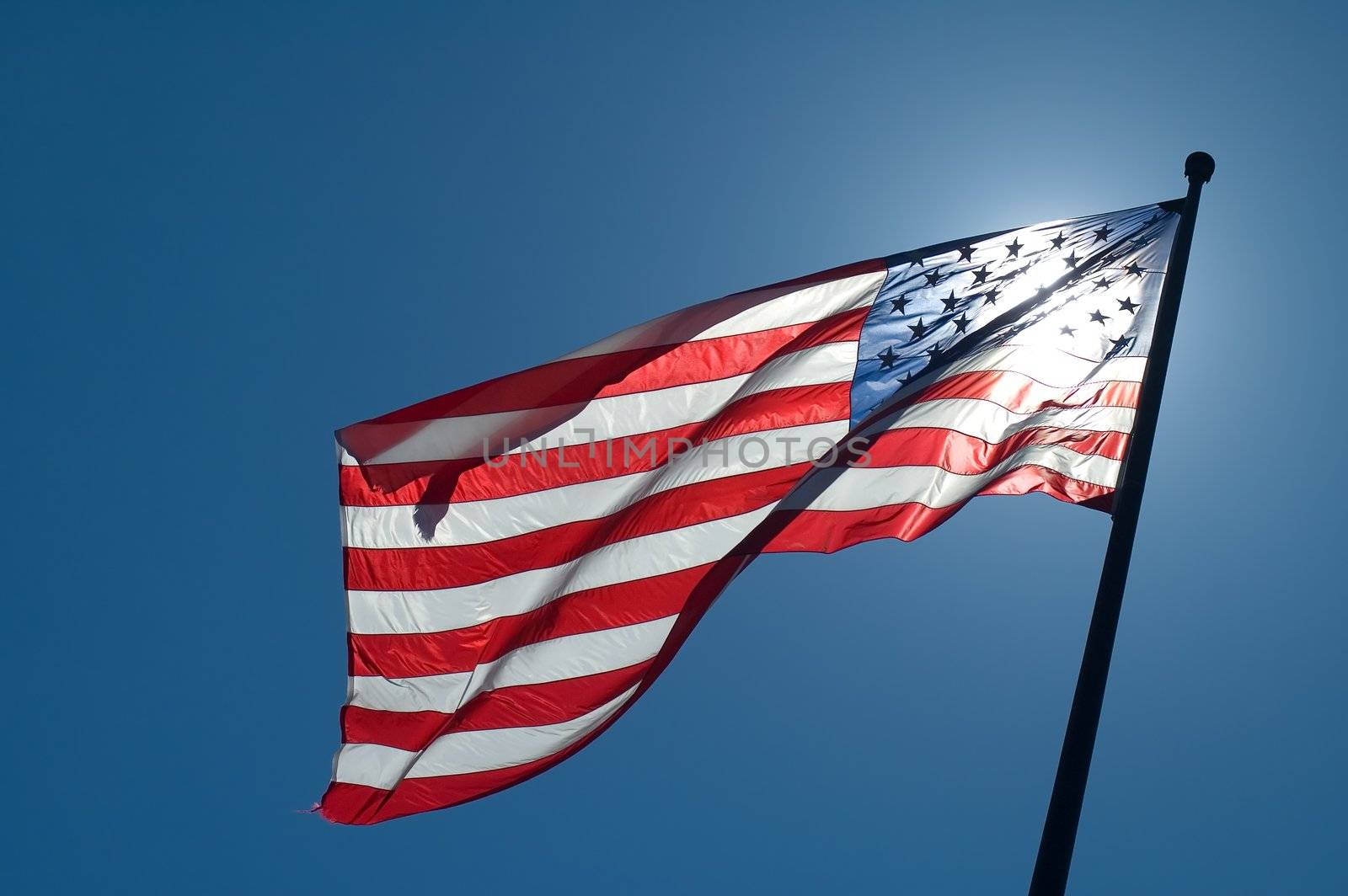 back lighted american flag, clear blue sky
