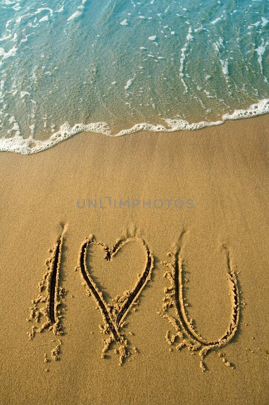 I love you written in sand on a beach, water in cyan color