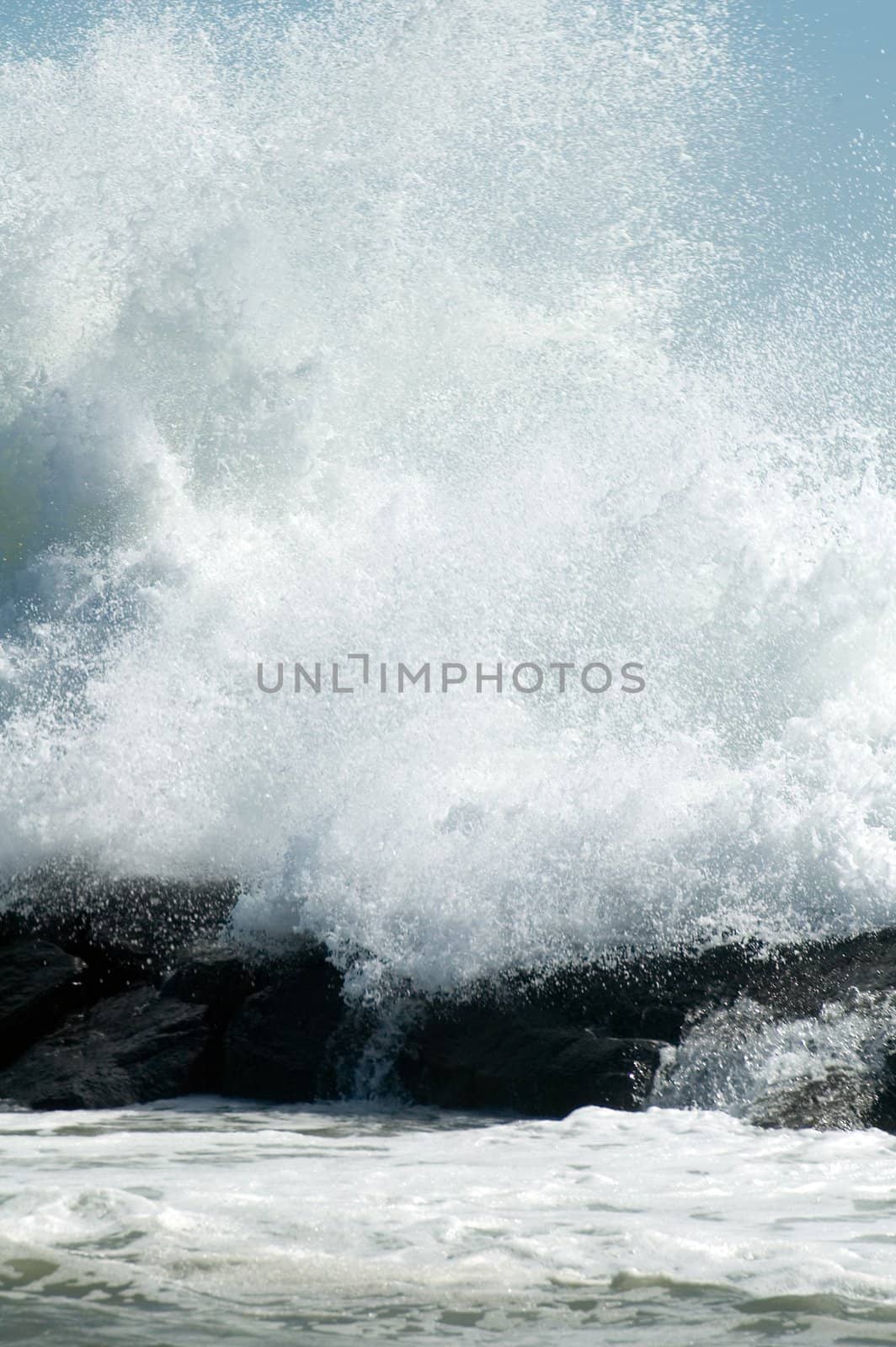 huge white wave crushing on coastline rocks