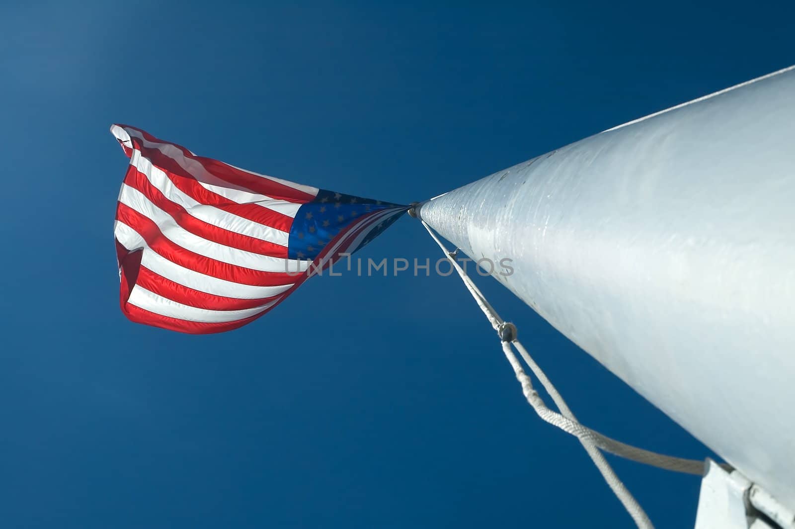 usa flag waving on a white pole, clear blue sky