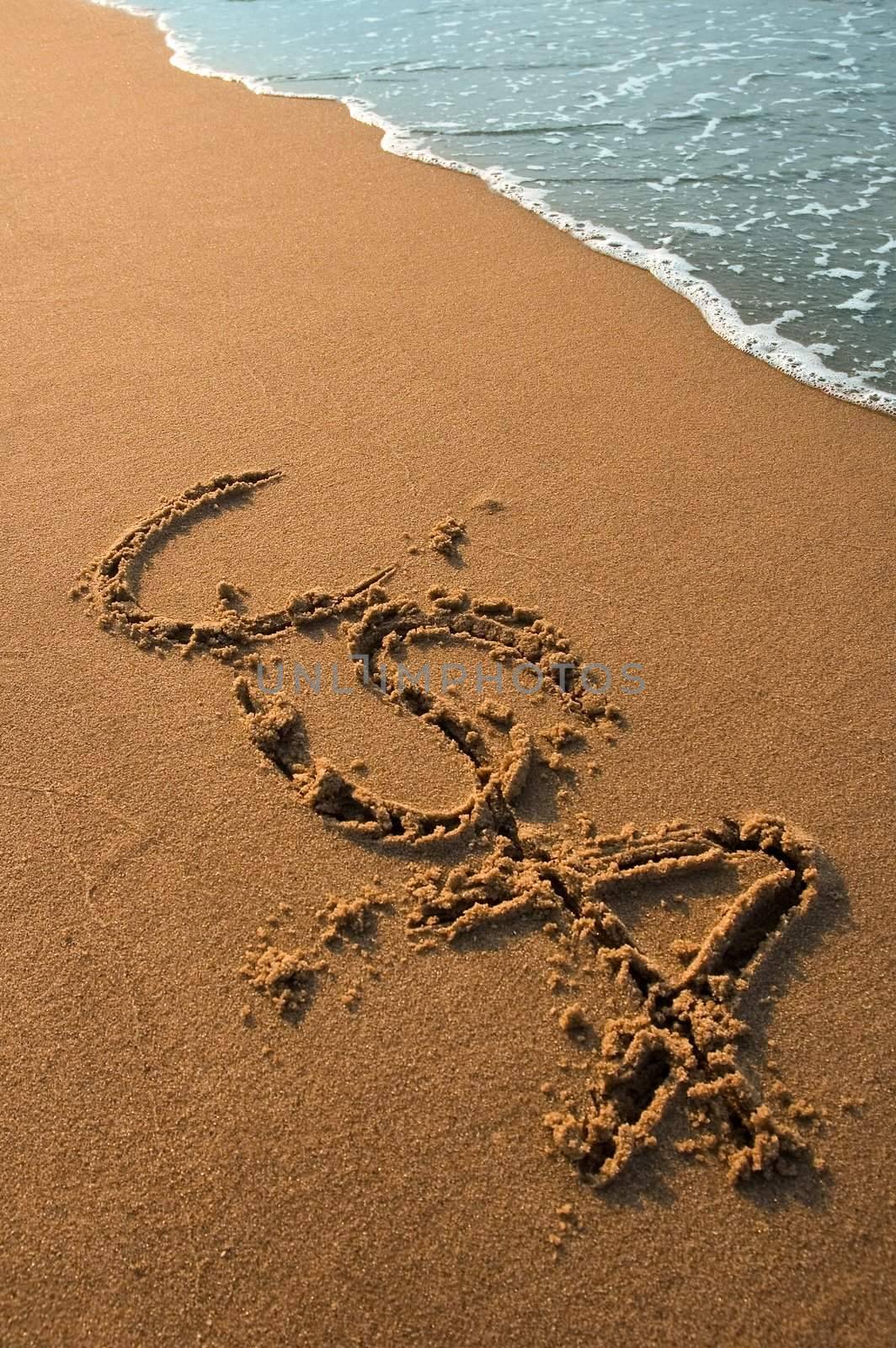 USA sign written in sand on a beach, cyan water in background, dusk photo