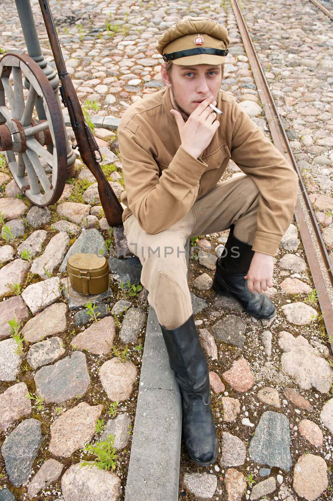 Soldier in uniform of World War I, sit down, resting on the pavement and smoking. Costume accord the times of World War I. Photo made at cinema city Cinevilla in Latvia. Cockade on the hat do not contain trade mark. 