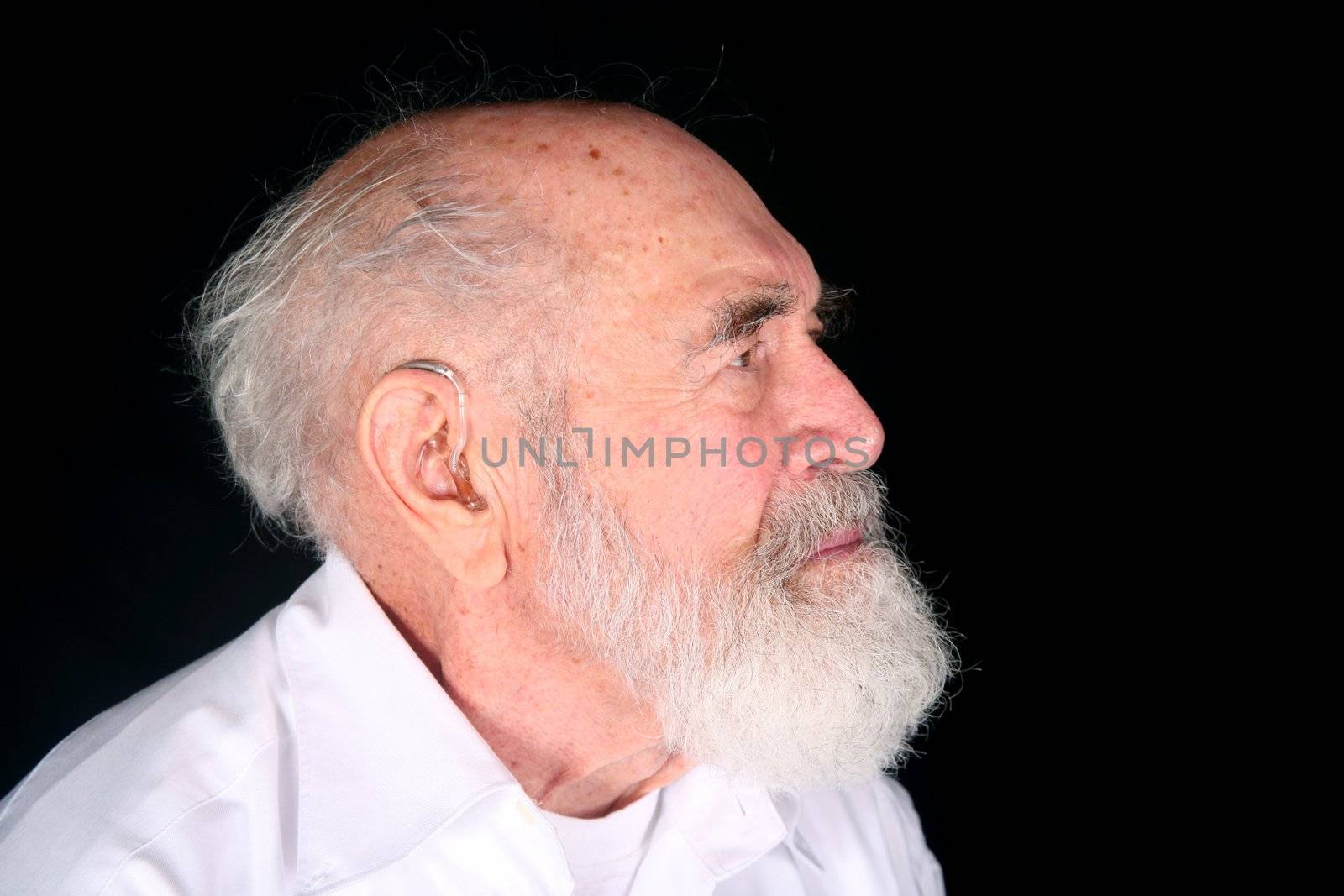 Grandfather wearing a custom hearing aid isolated on black background