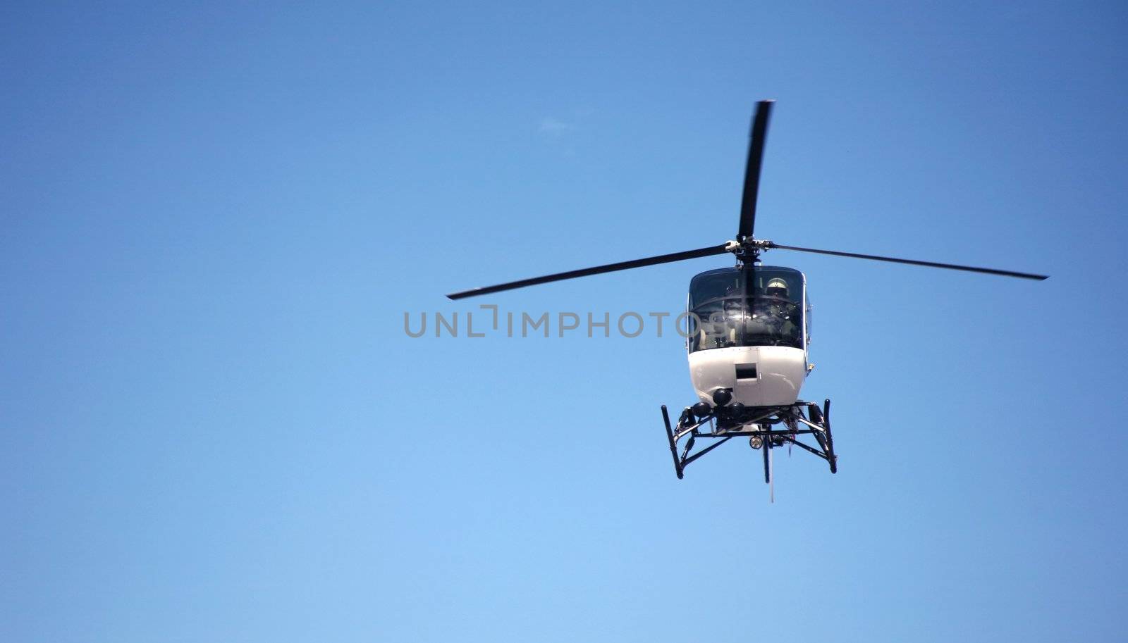 One police helicopter flying in the blue sky with blade motion visible