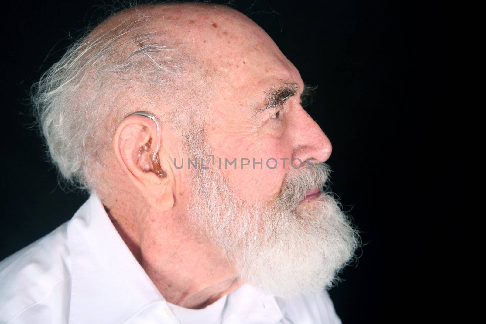 Grandfather wearing a hearing aid isolated on black background