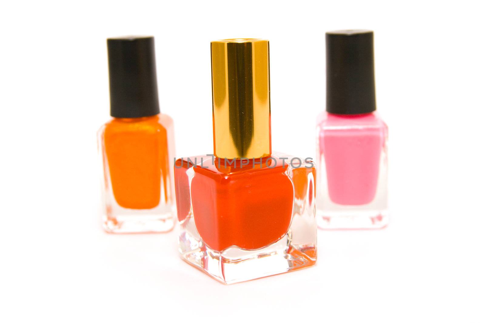 Three bottles of red, pink and orange nail polish on a white background 