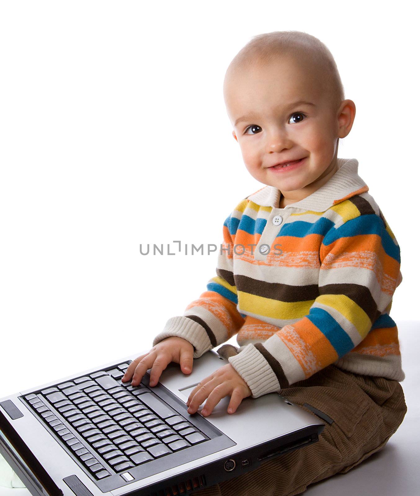 smiling little boy typing on laptop, isolated on white