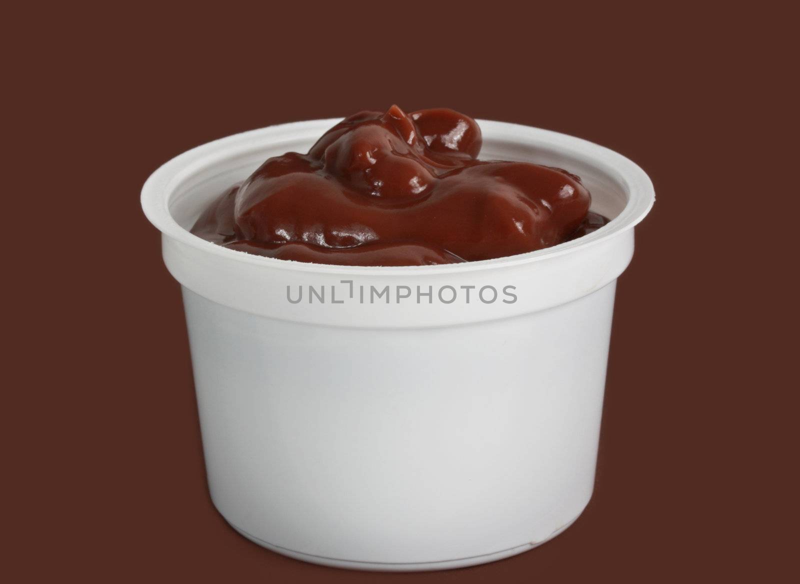 chocolate pudding in white plastic cup, brown background