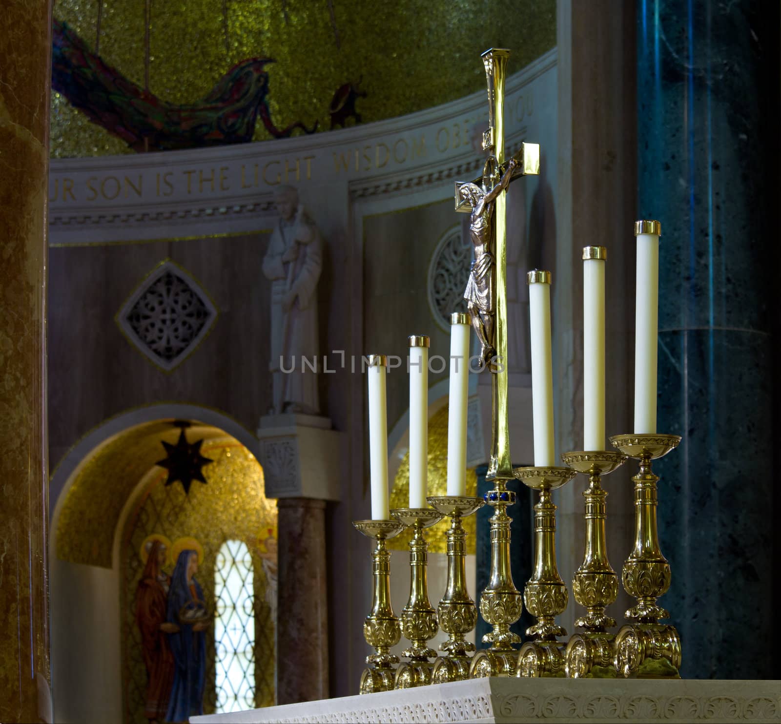 Ornate candlesticks on altar in church with gold cross by steheap