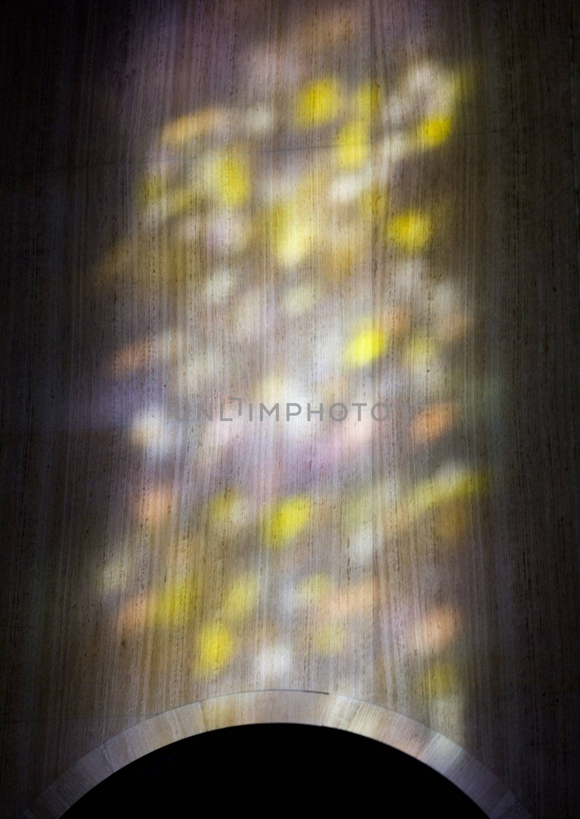 Colorful light from a stained glass window in a cathedral falls on the polished marble of the church