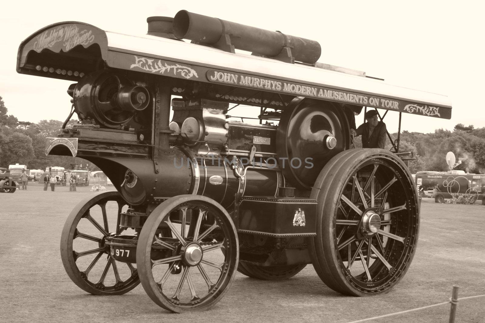 large black and blue traction steam engine at a steam rally in sepia tones