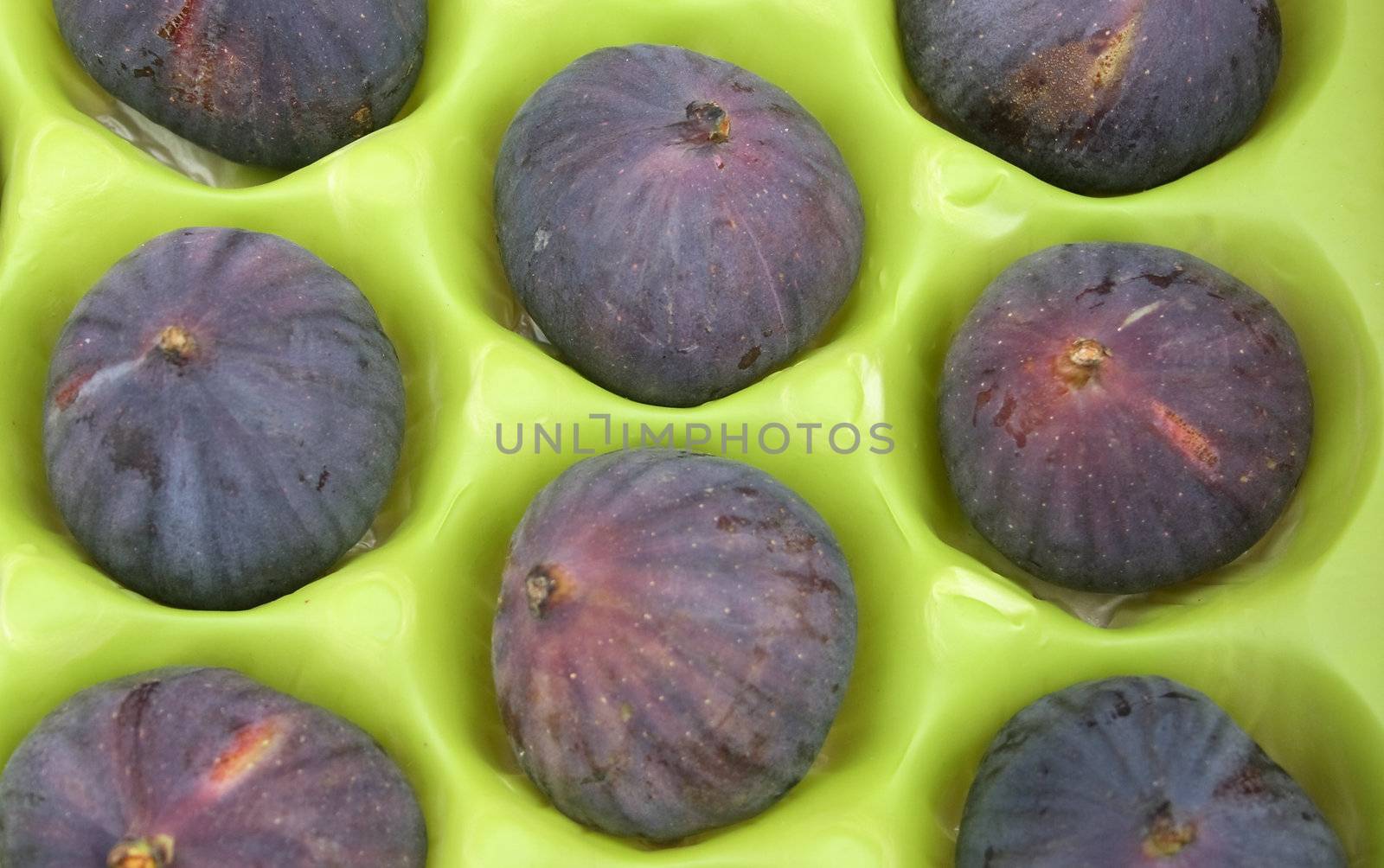 ripe fresh figs in green packaging background