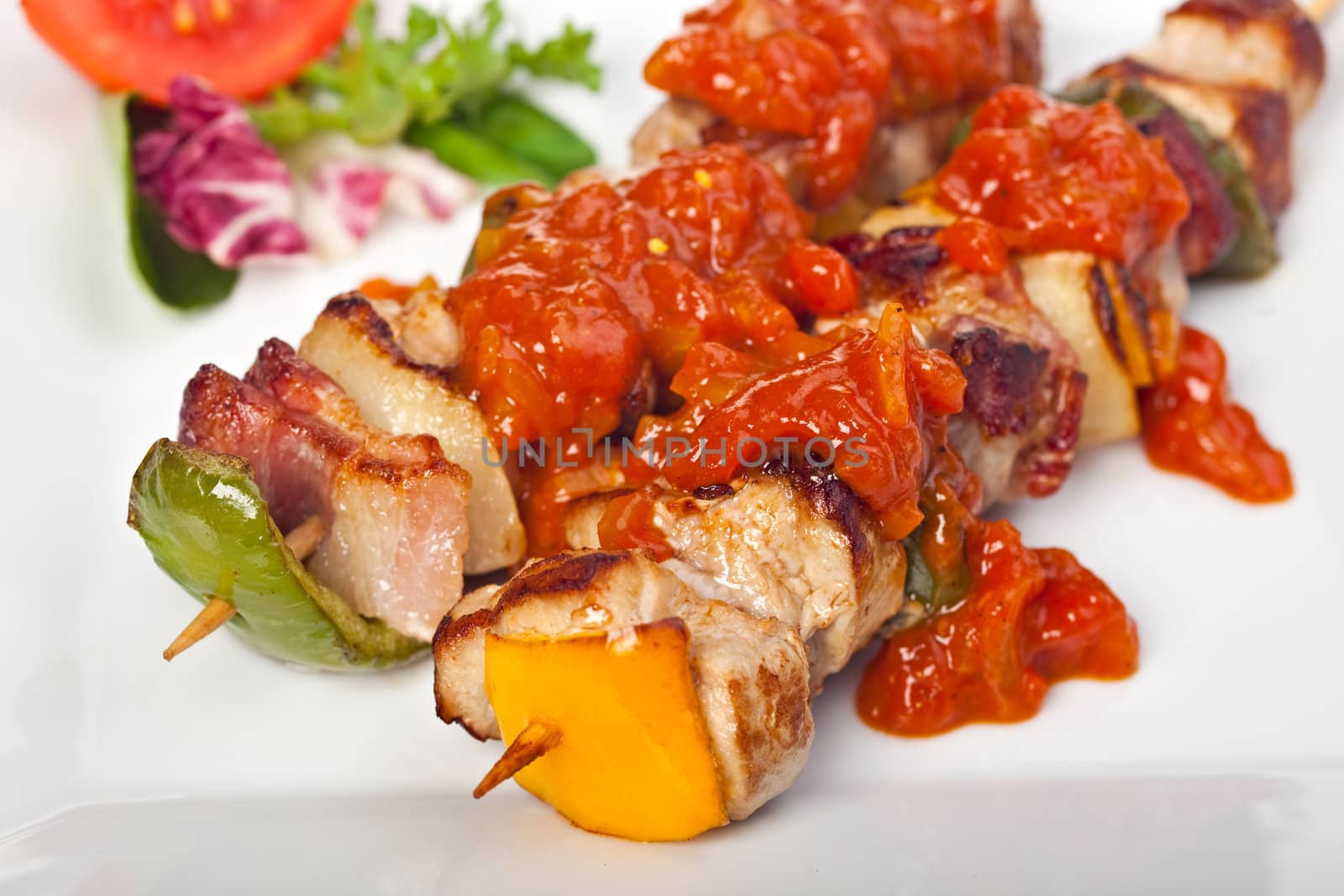 shashlik on a plate with a tomato and salad leaf