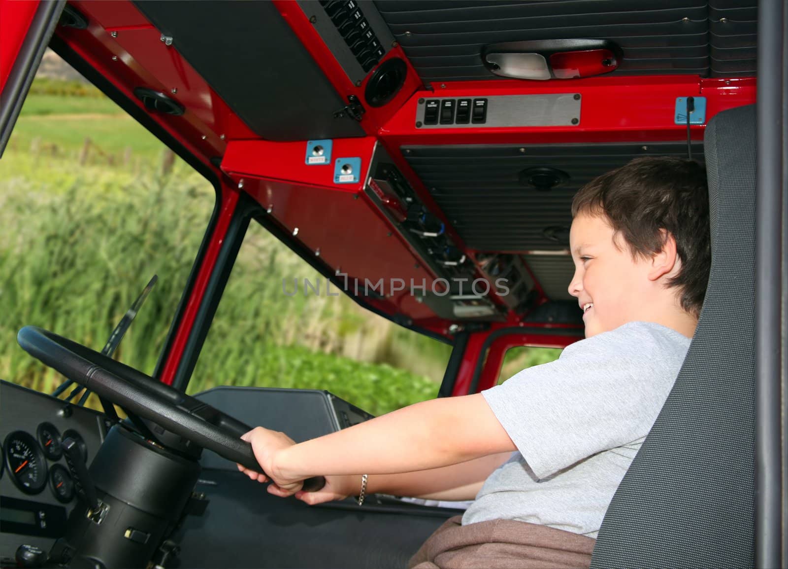 Young boy pretending to drive a fire truck