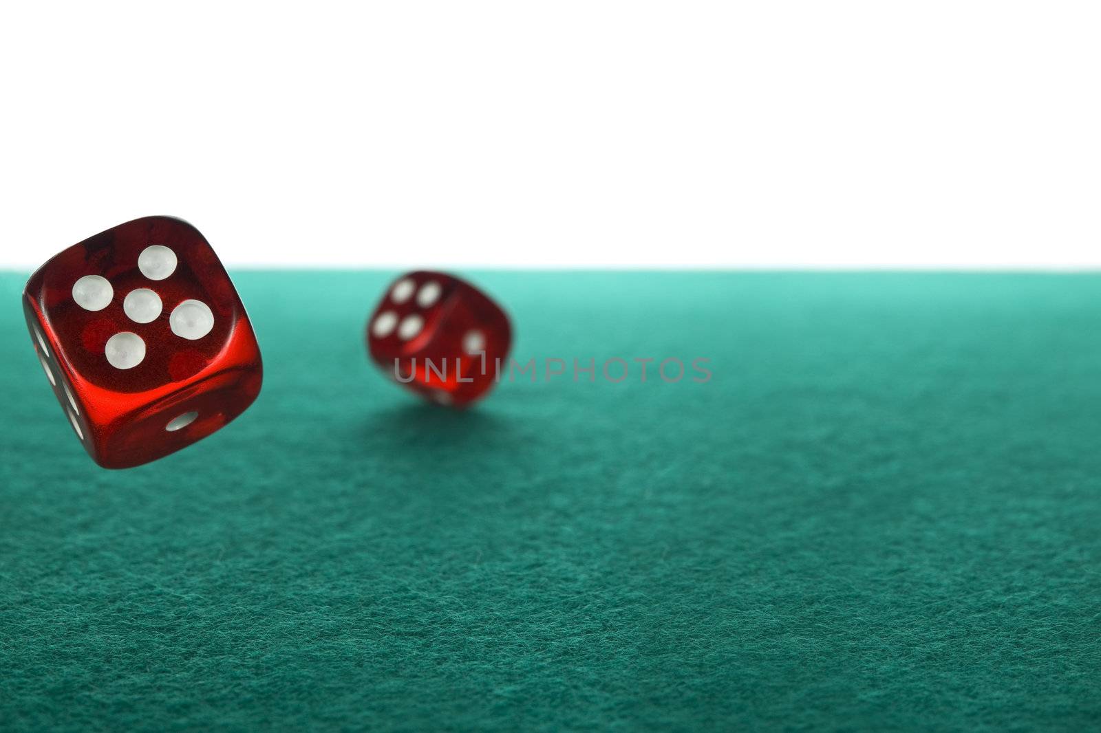 Two red dices rolling over a green felt against a white background.